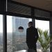 'The Mid-Year CEO Audit: 10 Questions Every UAE Business Leader Should Ask Themselves on June 30' : Image shows a businessman in a black suit looks out at skyscrapers from an office window, embracing an urban view.